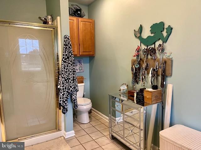 bathroom featuring toilet, tile patterned floors, and a shower with door