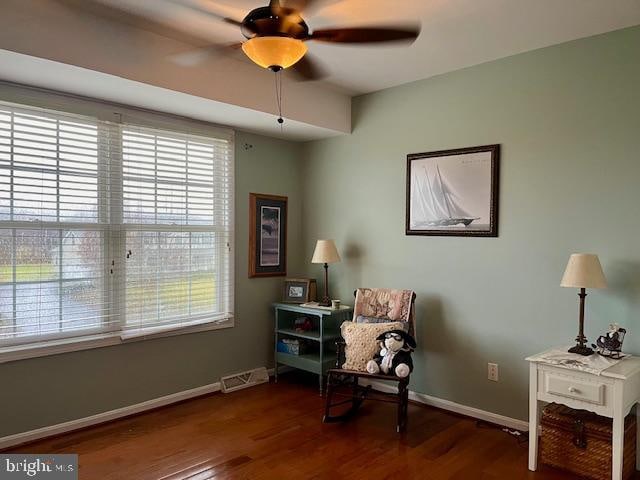 living area featuring ceiling fan and dark wood-type flooring