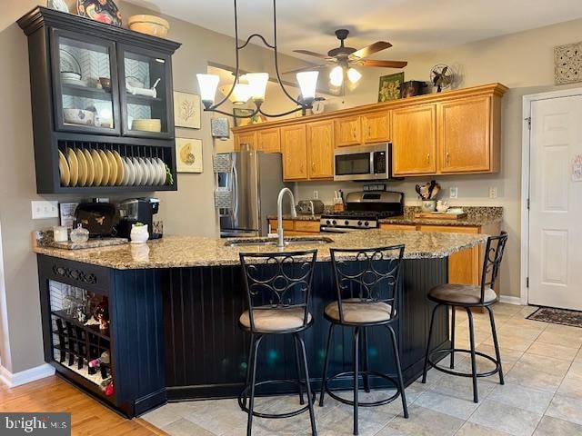 kitchen featuring light stone countertops, stainless steel appliances, a breakfast bar area, and sink