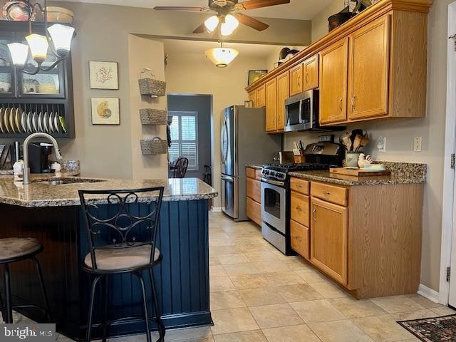 kitchen with a breakfast bar, stainless steel appliances, kitchen peninsula, and sink