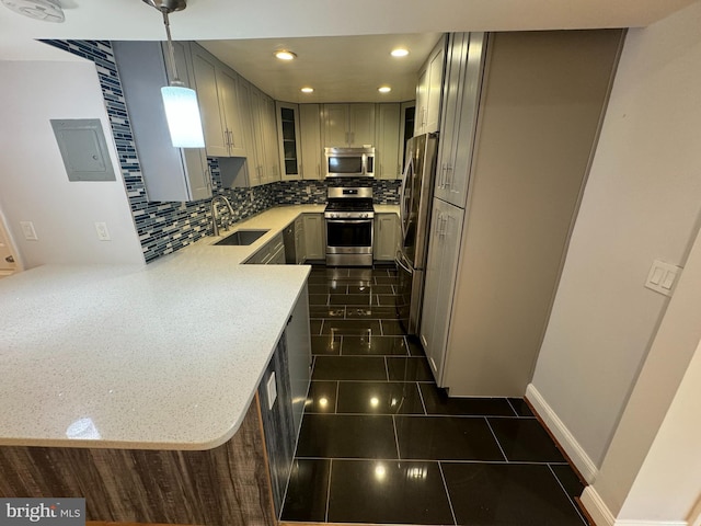 kitchen featuring kitchen peninsula, stainless steel appliances, sink, gray cabinets, and hanging light fixtures