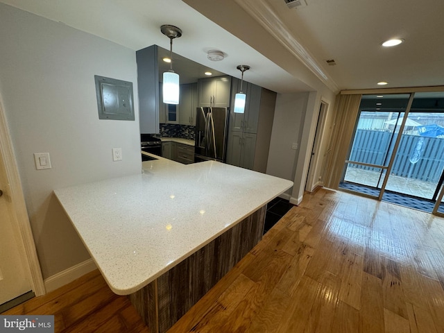 kitchen featuring stainless steel fridge with ice dispenser, kitchen peninsula, a breakfast bar area, and hardwood / wood-style flooring