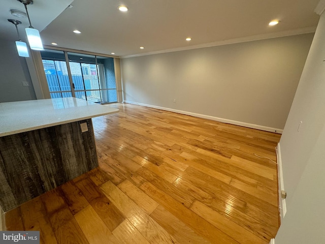 unfurnished living room featuring crown molding, light hardwood / wood-style flooring, and a wall of windows