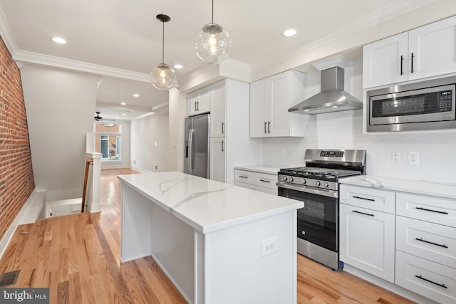 kitchen featuring wall chimney exhaust hood, a kitchen island, stainless steel appliances, and white cabinetry