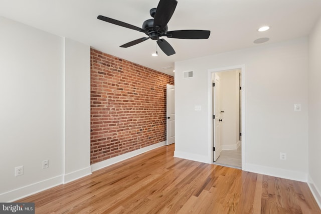 spare room with ceiling fan, brick wall, and light hardwood / wood-style flooring