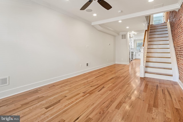 unfurnished living room featuring ceiling fan, ornamental molding, light hardwood / wood-style floors, and brick wall