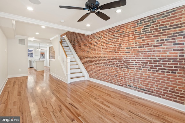 unfurnished living room with ceiling fan, light wood-type flooring, brick wall, and ornamental molding