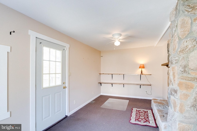 entryway with ceiling fan and dark carpet