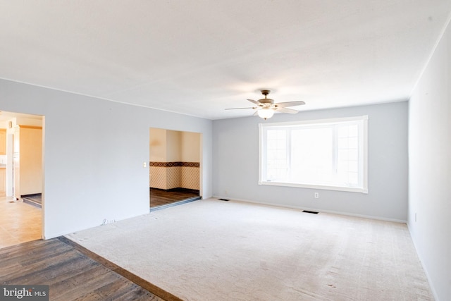 unfurnished room with ceiling fan and carpet