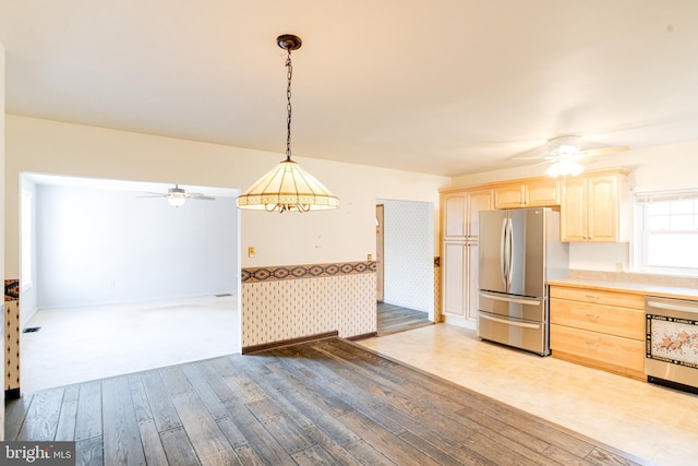 kitchen with light brown cabinetry, stainless steel refrigerator, pendant lighting, ceiling fan, and hardwood / wood-style floors