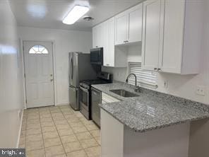 kitchen featuring kitchen peninsula, appliances with stainless steel finishes, white cabinets, and sink