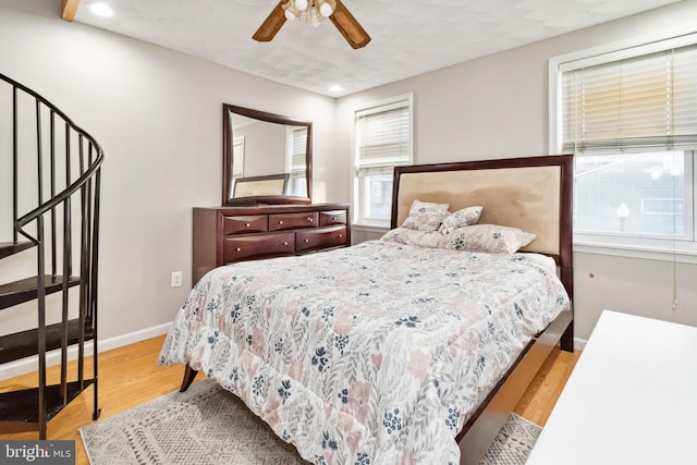 bedroom featuring ceiling fan, wood-type flooring, and multiple windows