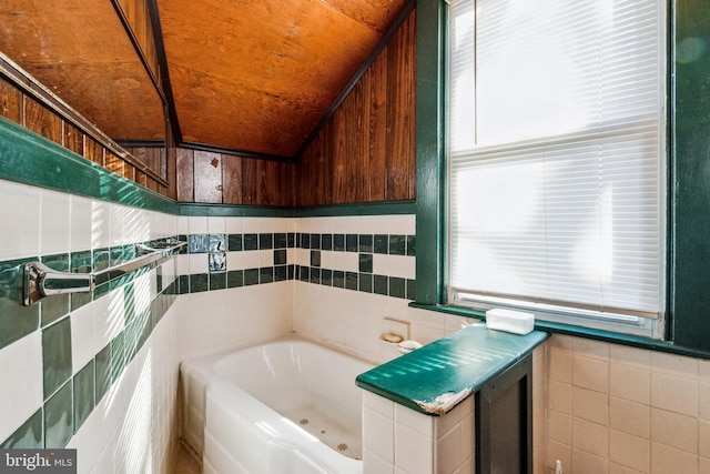 bathroom with a tub to relax in, tile walls, and lofted ceiling