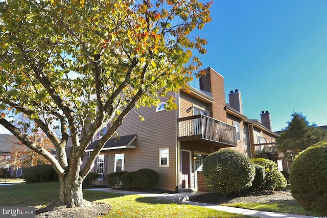 view of front of home with a balcony and a front yard