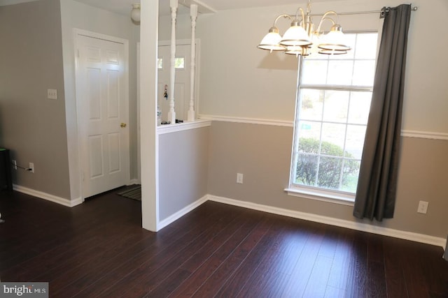 unfurnished dining area featuring dark hardwood / wood-style floors and an inviting chandelier