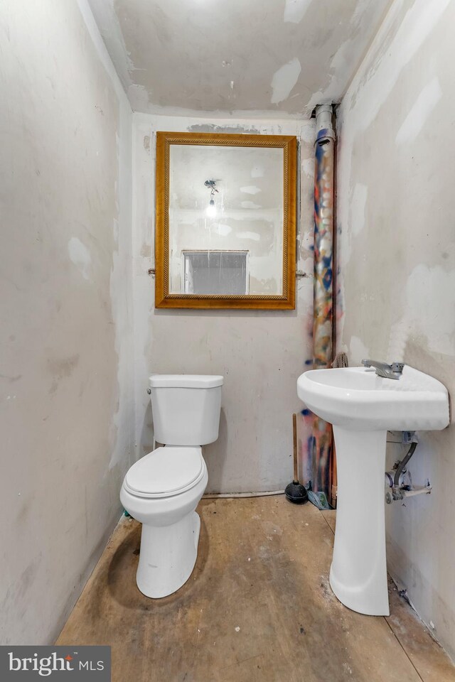 bathroom featuring concrete floors, toilet, and sink