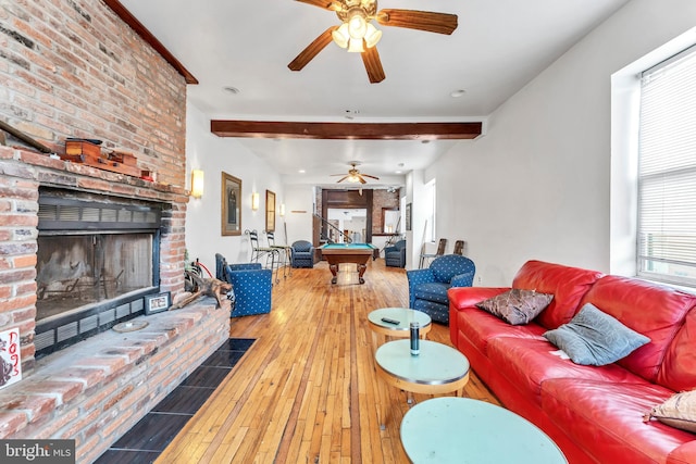 living room featuring a brick fireplace, ceiling fan, beam ceiling, hardwood / wood-style flooring, and pool table