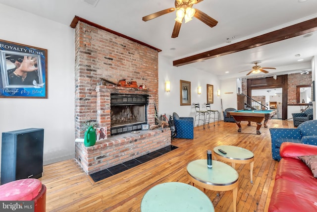 living room featuring ceiling fan, wood-type flooring, beamed ceiling, billiards, and a fireplace