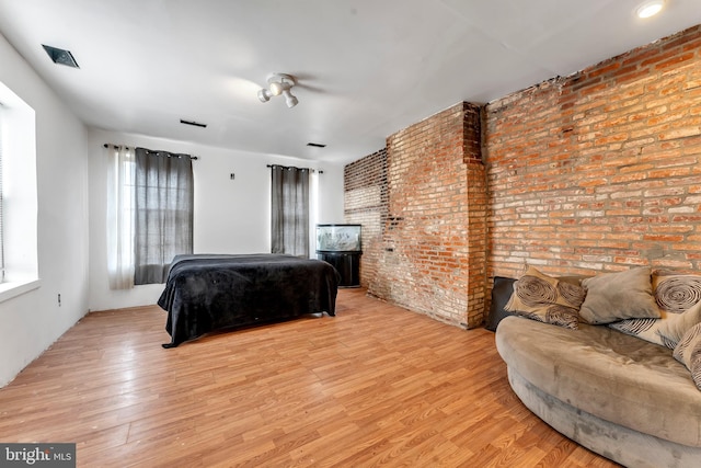 bedroom featuring light hardwood / wood-style floors and brick wall