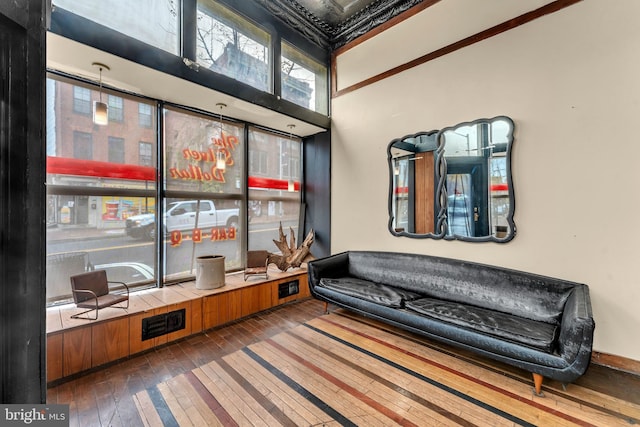 living area with wood-type flooring and ornamental molding