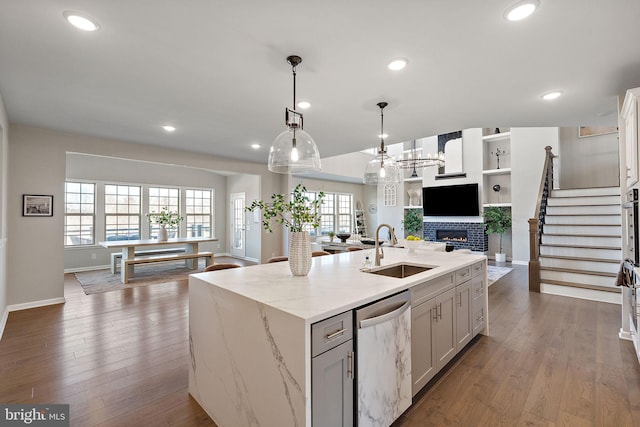 kitchen featuring dishwasher, a kitchen island with sink, sink, decorative light fixtures, and white cabinetry