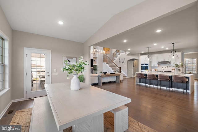 dining space with a chandelier, lofted ceiling, dark wood-type flooring, and sink