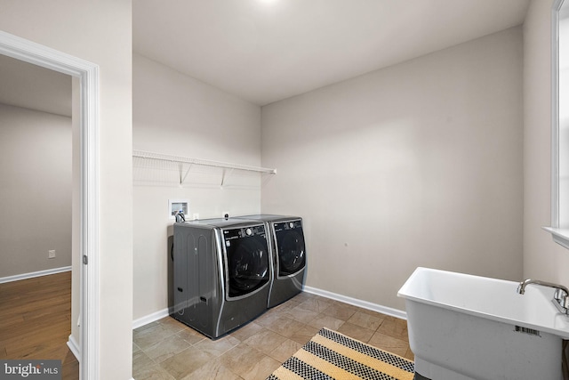 clothes washing area with washing machine and clothes dryer, sink, and light hardwood / wood-style floors