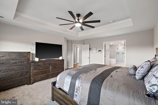 carpeted bedroom featuring ceiling fan, a raised ceiling, ornamental molding, and ensuite bath