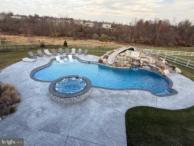 view of pool with a patio area, a water slide, and a rural view