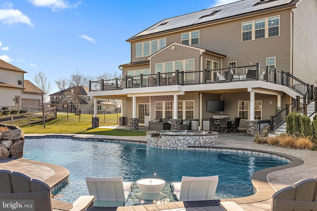 rear view of house featuring a yard, a balcony, a patio, and solar panels