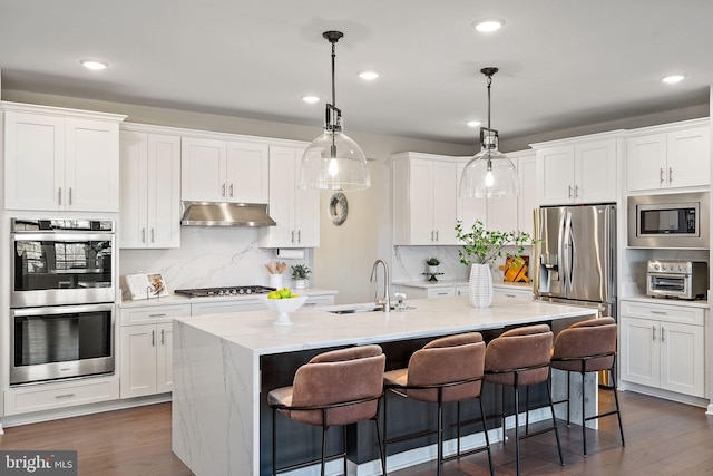 kitchen with a center island with sink, white cabinetry, sink, and appliances with stainless steel finishes