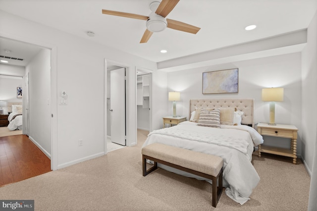 bedroom featuring a closet, a spacious closet, light hardwood / wood-style flooring, and ceiling fan