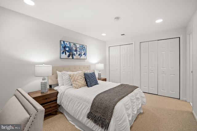 bedroom with light carpet and multiple closets