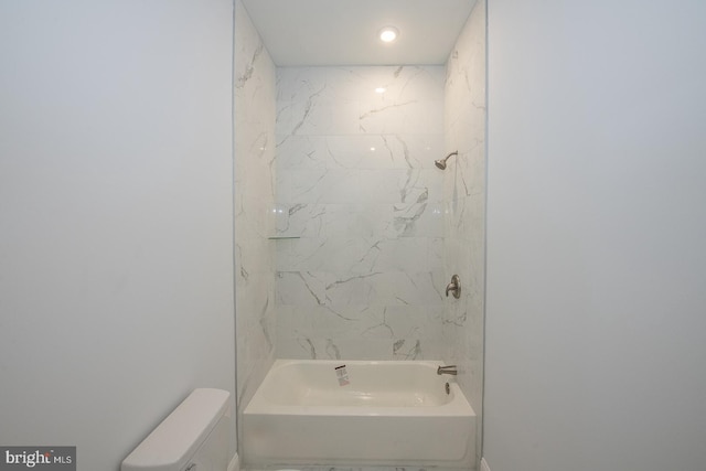 bathroom featuring toilet and tiled shower / bath