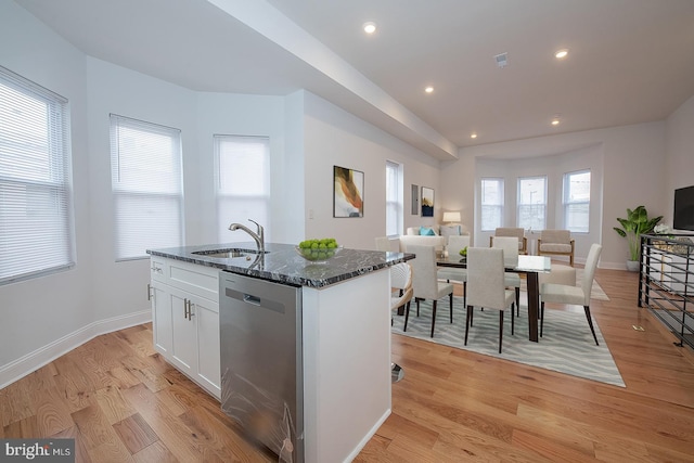 kitchen with dishwasher, dark stone counters, white cabinets, sink, and light hardwood / wood-style flooring