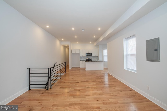 unfurnished living room featuring electric panel and light hardwood / wood-style floors