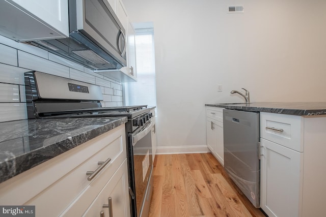 kitchen featuring white cabinets, decorative backsplash, stainless steel appliances, and light hardwood / wood-style floors