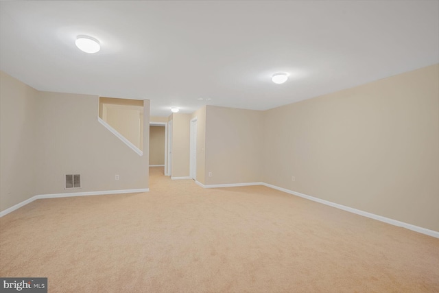 finished basement with visible vents, light carpet, and baseboards