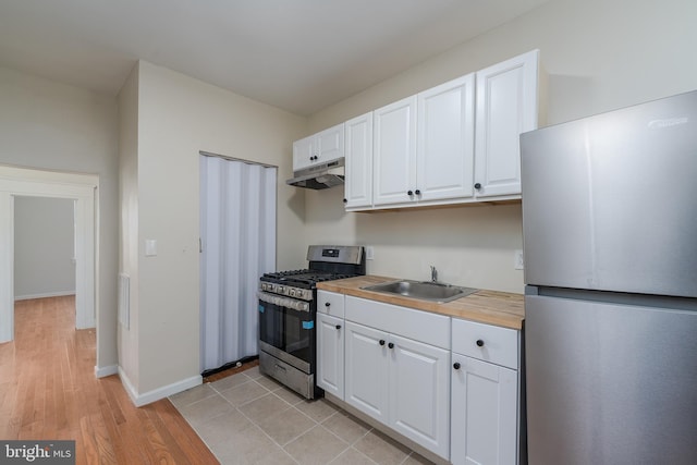 kitchen with butcher block countertops, sink, stainless steel appliances, light hardwood / wood-style floors, and white cabinets