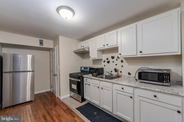 kitchen featuring stainless steel appliances, light stone countertops, sink, and white cabinets