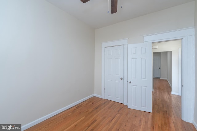 unfurnished bedroom featuring ceiling fan, a closet, and light wood-type flooring