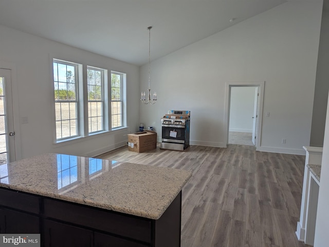 kitchen featuring light stone counters, baseboards, light wood-style floors, stainless steel range with gas cooktop, and an inviting chandelier