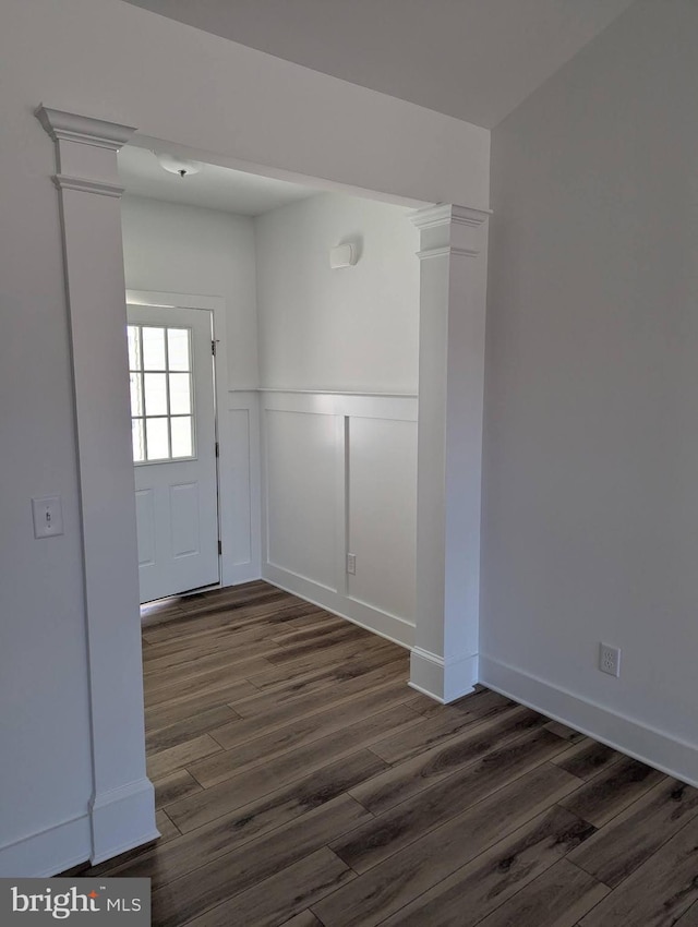 entrance foyer with a wainscoted wall, dark wood-type flooring, decorative columns, and a decorative wall