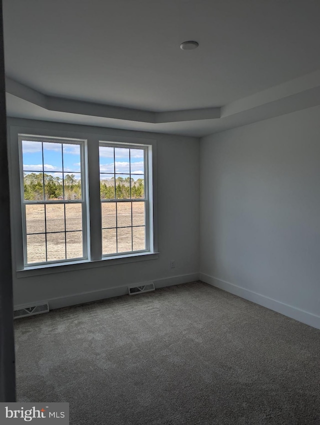 spare room with carpet flooring, visible vents, and baseboards