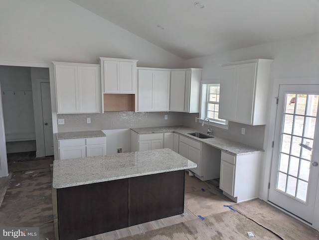 kitchen with lofted ceiling, a wealth of natural light, a kitchen island, and a sink