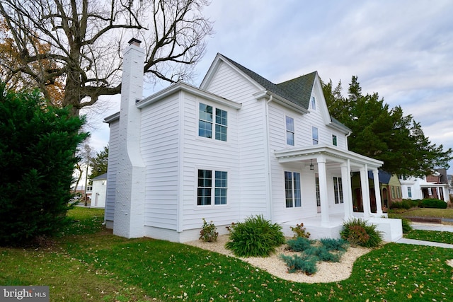 view of side of property featuring covered porch and a yard