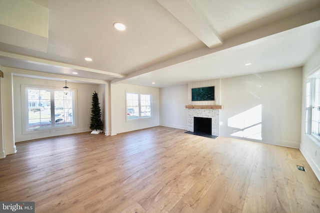 unfurnished living room with beamed ceiling and light hardwood / wood-style floors