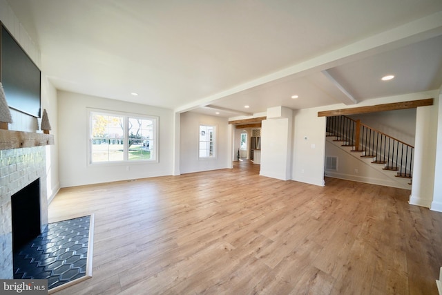 unfurnished living room with beamed ceiling and light hardwood / wood-style flooring