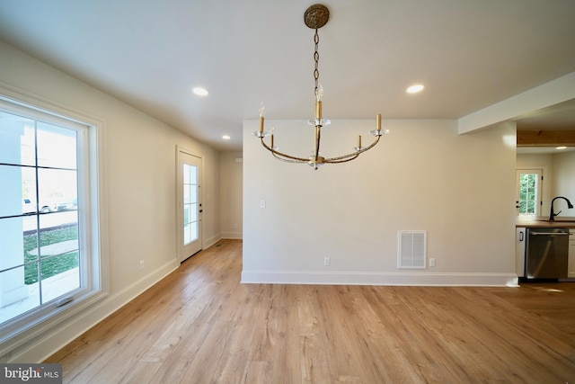 unfurnished dining area featuring light hardwood / wood-style flooring, a notable chandelier, and sink