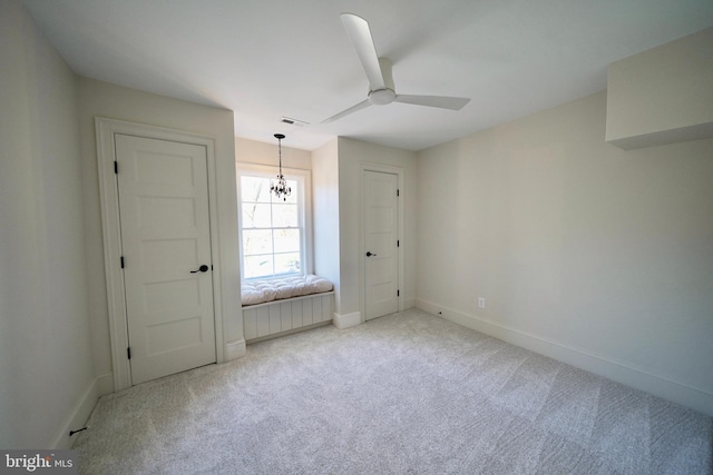 unfurnished bedroom with light colored carpet and ceiling fan with notable chandelier